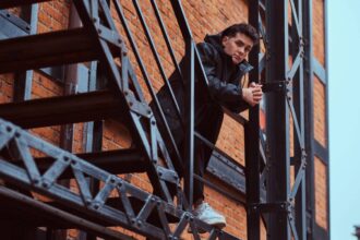 Jeune homme s'appuyant sur un garde-corps d'escalier extérieur