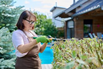 Jardinier taillant une haie dans un jardin verdoyant
